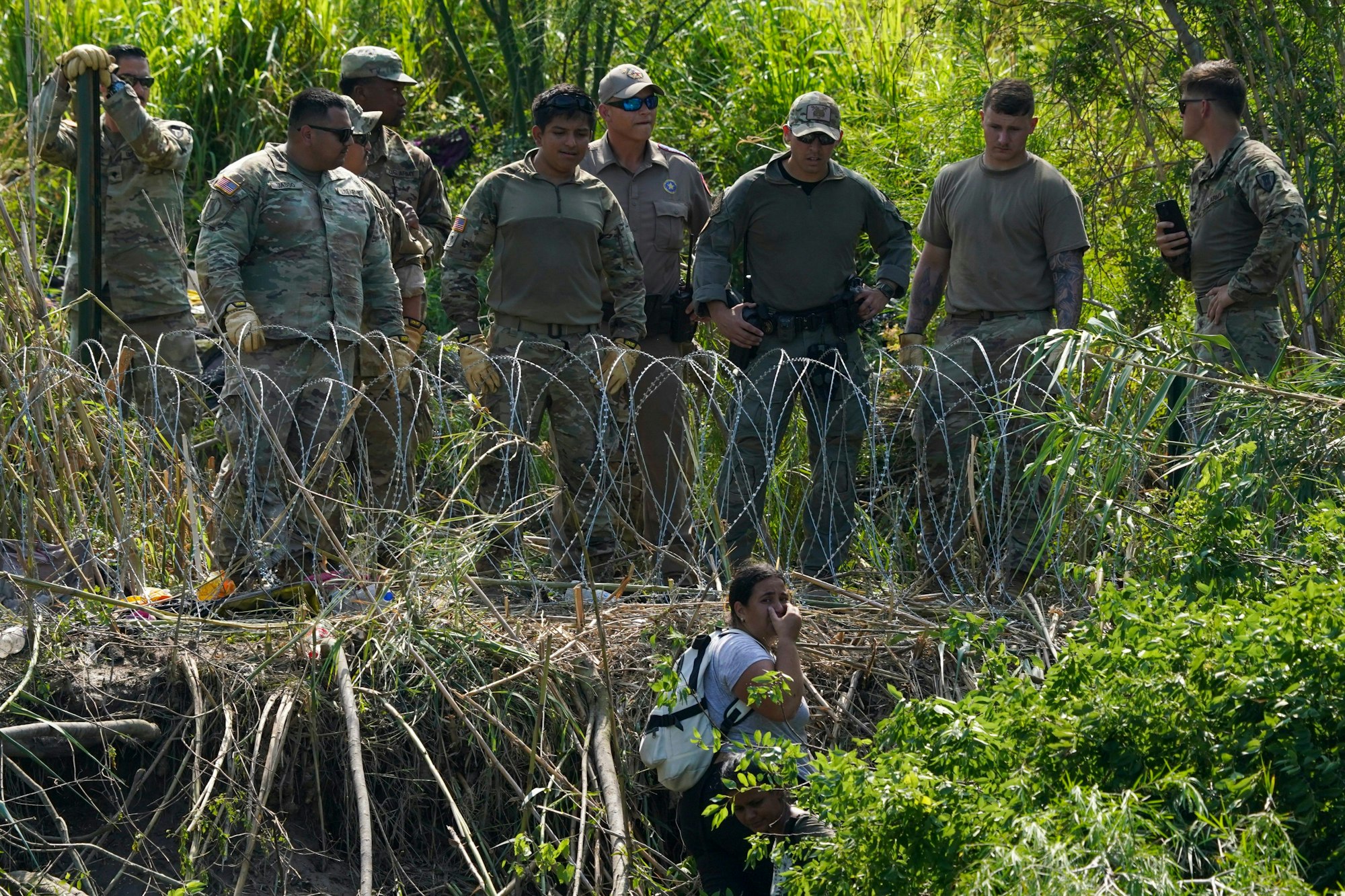 Matamoros: Texanische Polizisten stehen hinter einer Barriere aus Natodraht am Ufer des Rio Grande, während eine Migrantin auf der mexikanischen Seite weint.