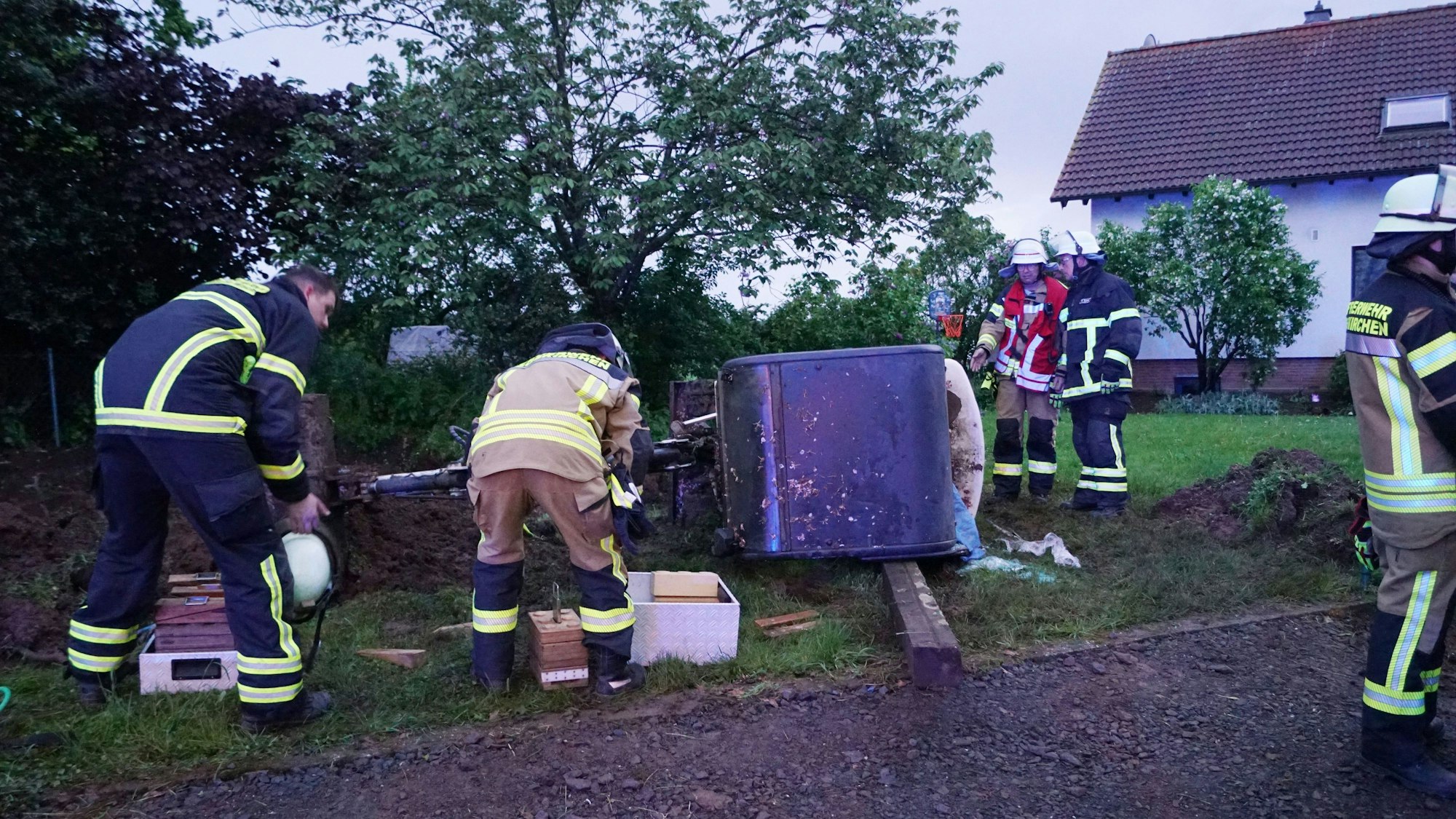 Der Bagger liegt auf der Seite und Feuerwehrleute sind an der Unfallstelle.