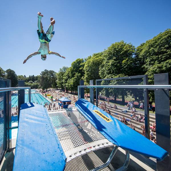 Ein Mann macht kopfüber einen Sprung im Stadionfreibad.