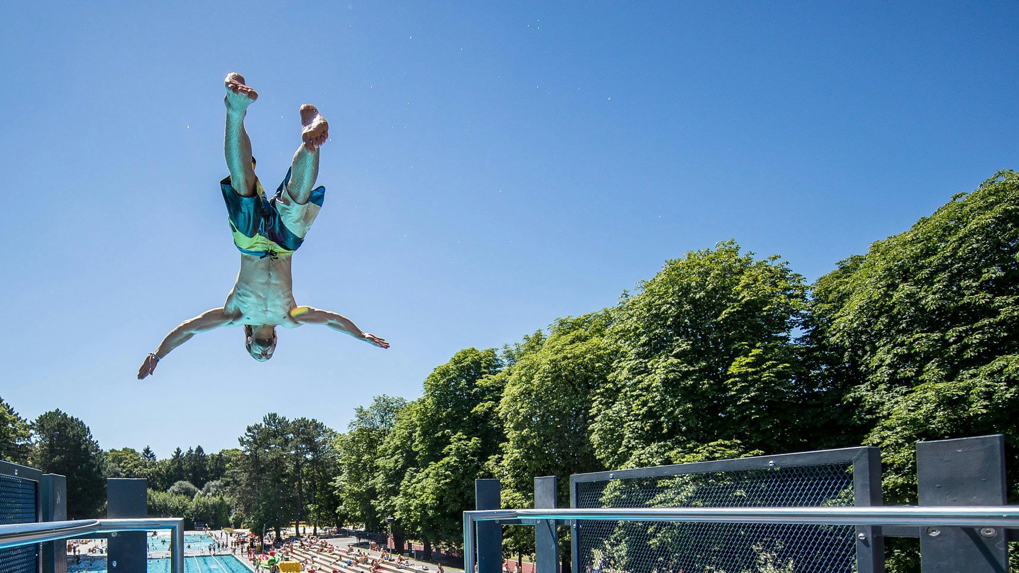 Ein Mann macht kopfüber einen Sprung im Stadionfreibad.