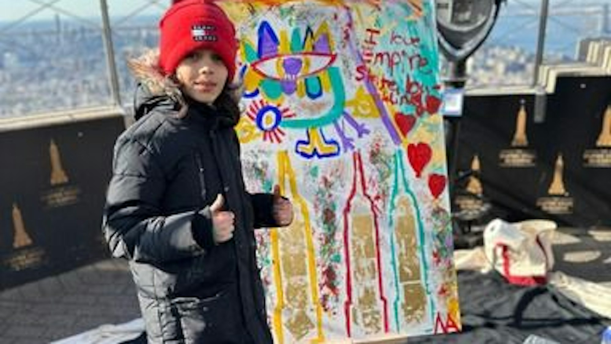 Auf dem Foto ist der junge Künstler auf dem Empire State Building in New York zu sehen. Dort hat er in luftiger Höhe ein Kunstwerk geschaffen.