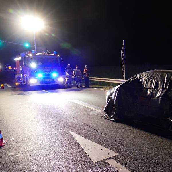 Ein Einsatzfahrzeug der Feuerwehr steht auf der Straße. Ebenso das Auto des Opfers.