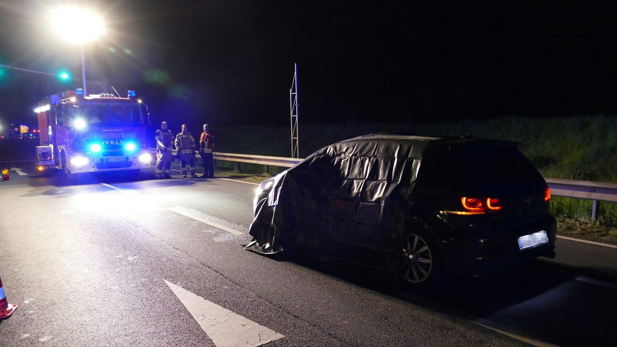 Ein Einsatzfahrzeug der Feuerwehr steht auf der Straße. Ebenso das Auto des Opfers.