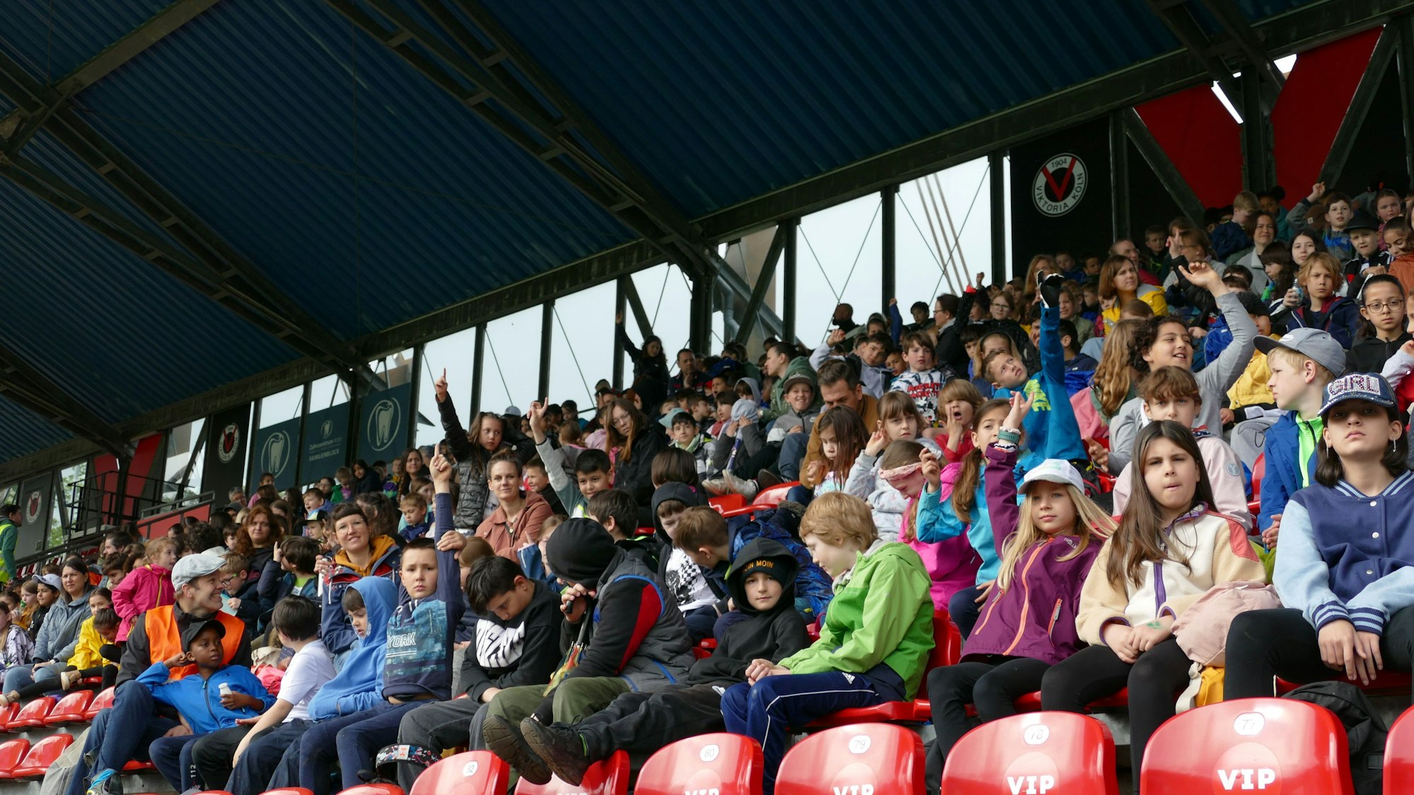 Kinder sitzen auf einer Tribüne.