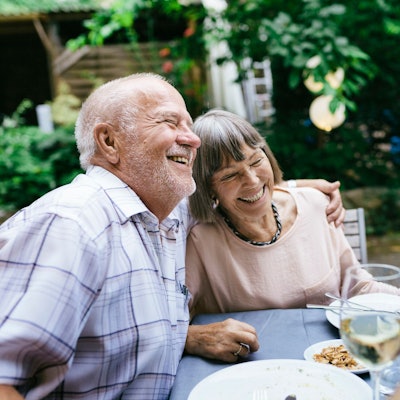 Ein älteres Paar genießt das Essen im Garten mit Freunden.