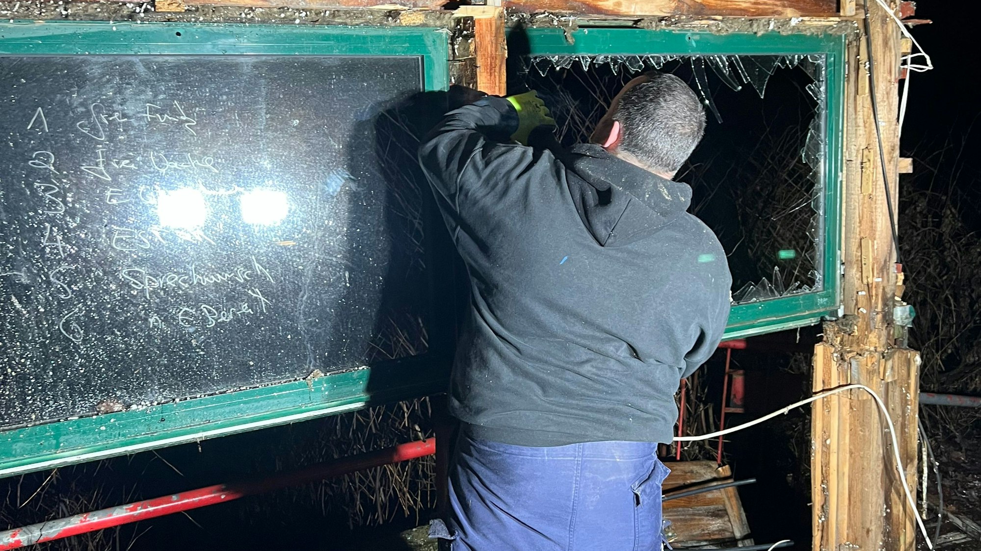 Ein Mann ist von hinten zu sehen, wie er in einem Rohbau Abrissarbeiten durchführt.