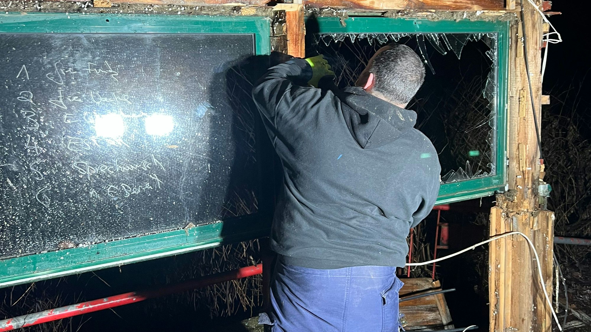 Ein Mann ist von hinten zu sehen, wie er in einem Rohbau Abrissarbeiten durchführt.