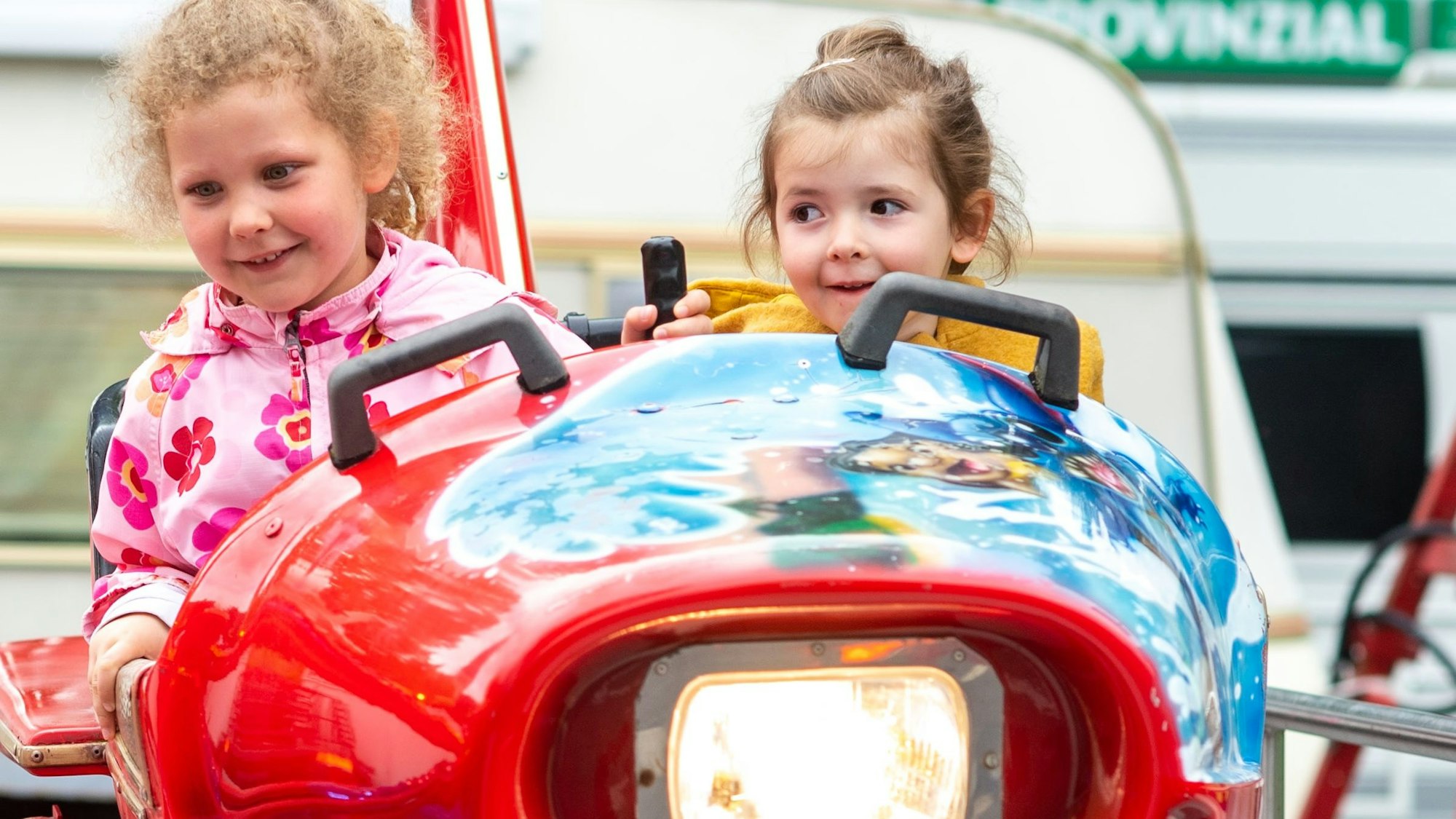 Zwei junge Mädchen sitzen in einem Fahrgeschäft in einem Flugzeug.