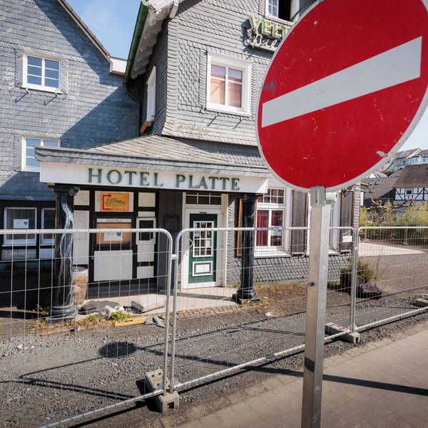 Vor einem eingezäunten Hotel steht im Vordergrund ein Stop-Schild.