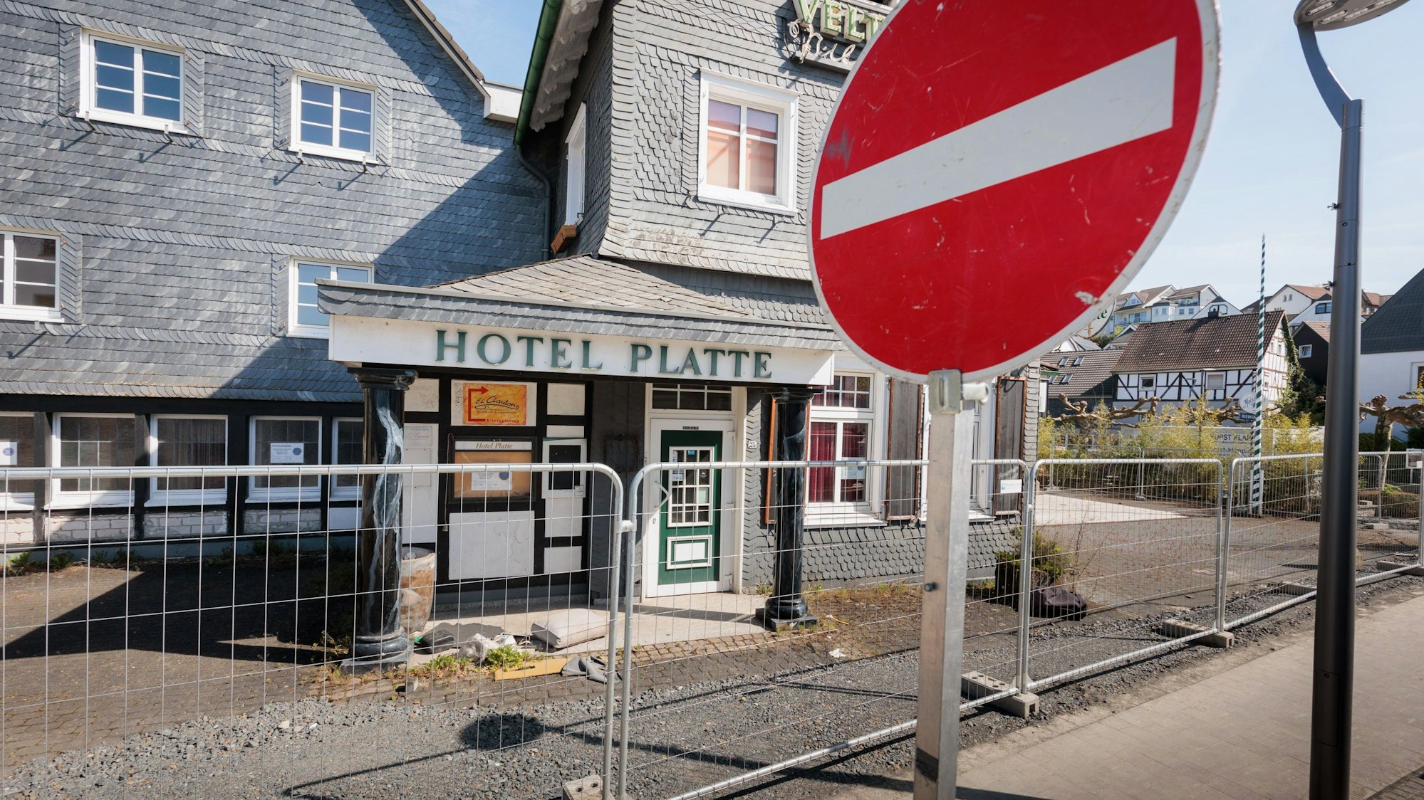 Vor einem eingezäunten Hotel steht im Vordergrund ein Stop-Schild.
