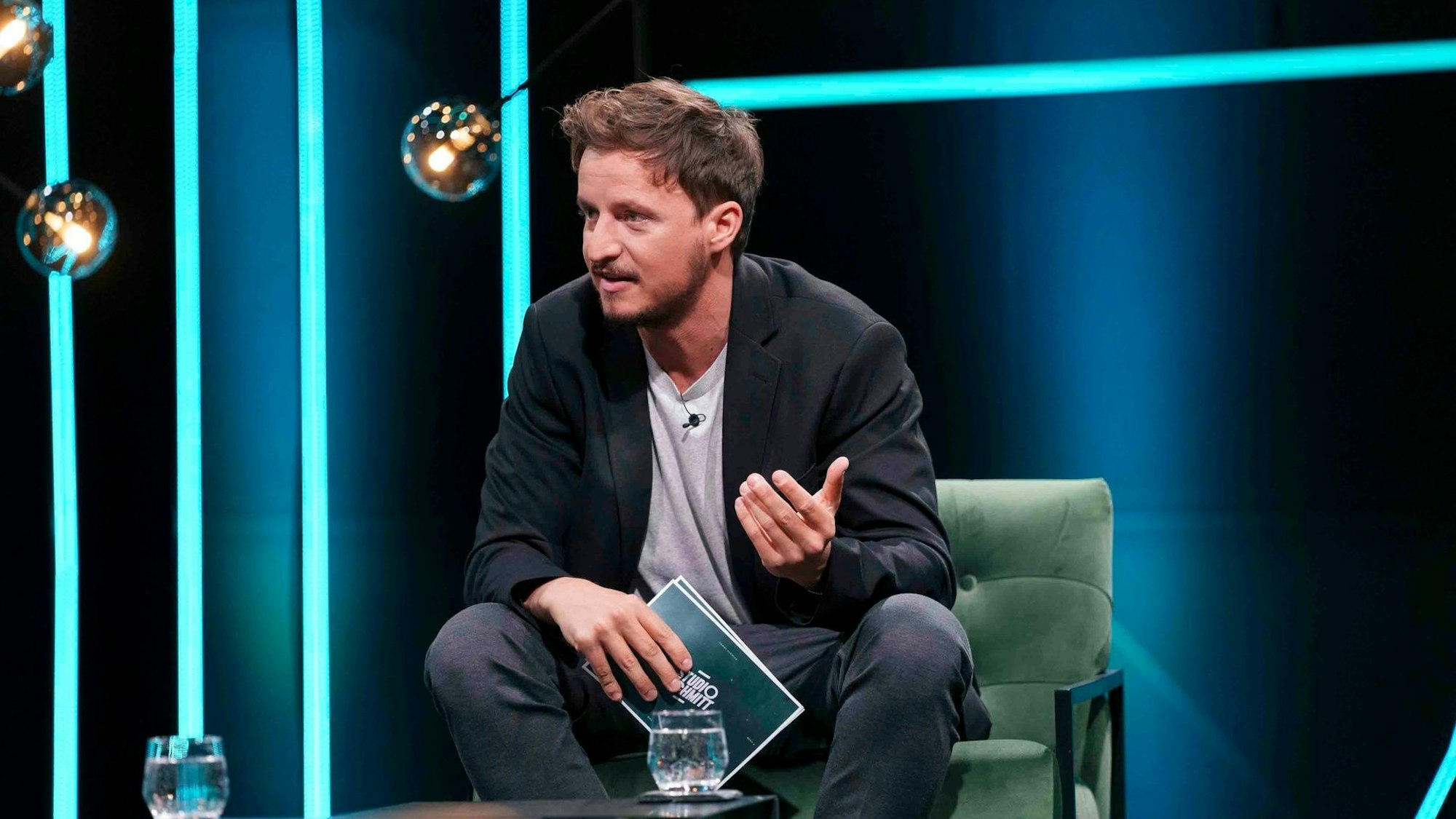 Tommi Schmitt sitzt in einem Sessel im TV-Studio.