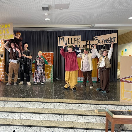 Theateraufführung bei der Feier 50 Jahre Gutenbergschule. Kinderschauspieler und Kinderschauspielerinnen halten Schilder hoch und schauen in die Kamera.