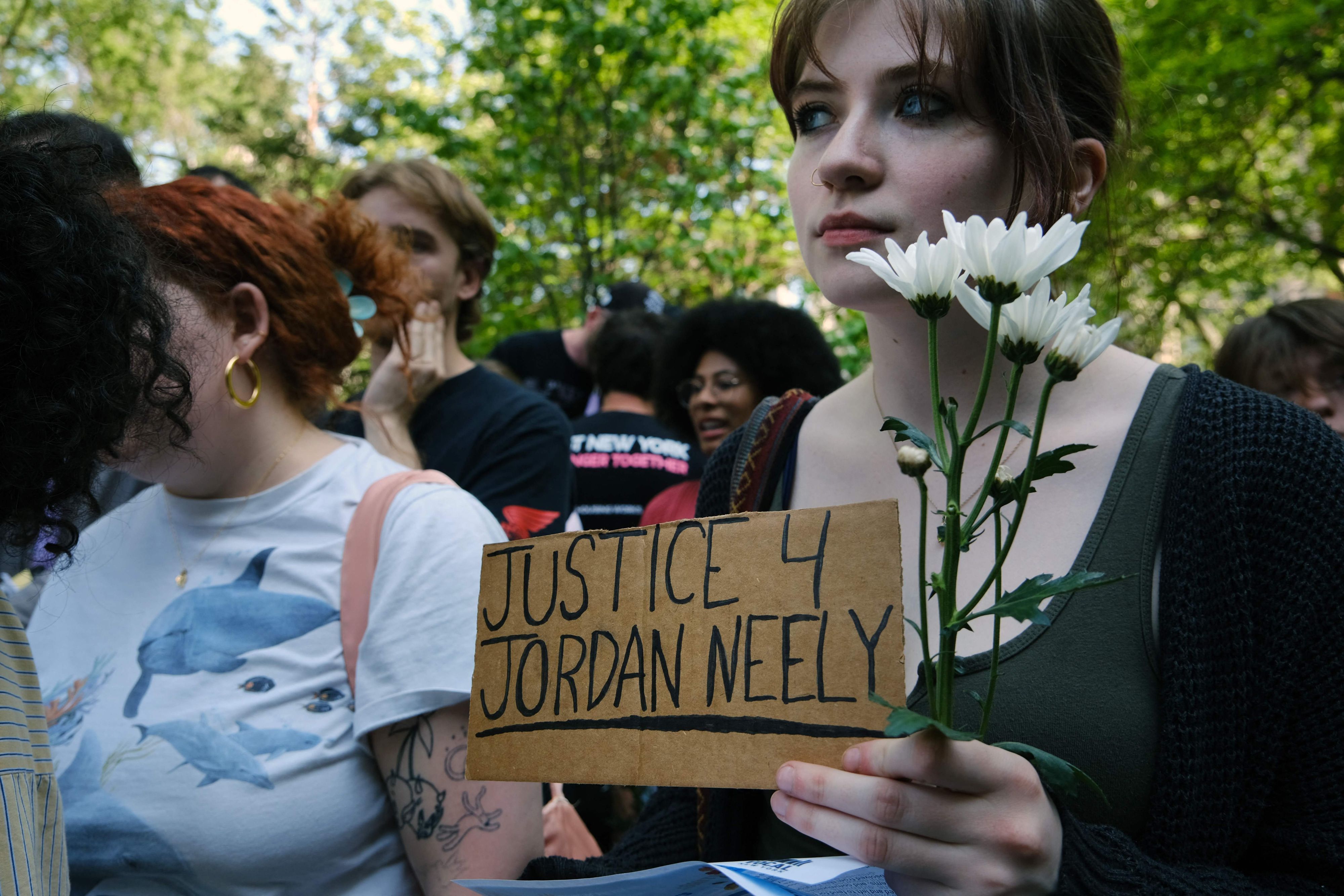 Eine Frau hält ein Schild mit der Aufschrift „Justice 4 Jordan Neely“.