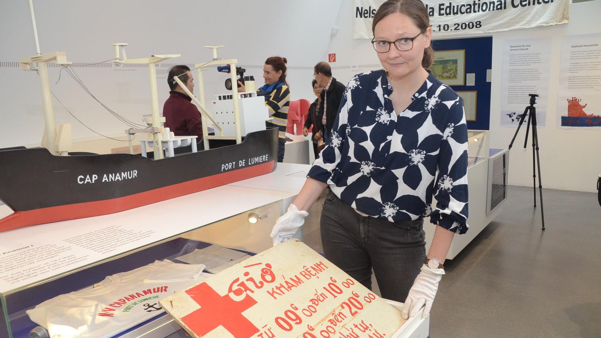 Das Schild, das die Öffnungszeiten der Krankenstation nannte, wird von Kuratorin Bernadette Fischer gezeigt.