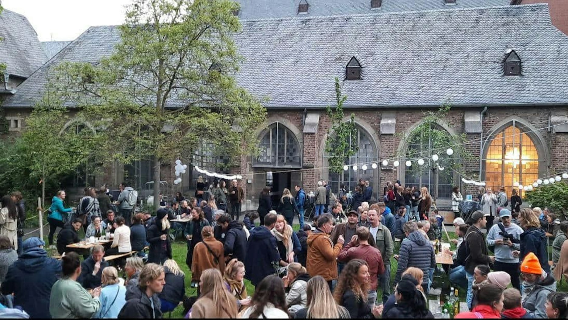 Menschen stehen im Garten der Kartäuserkirchengemeinde.