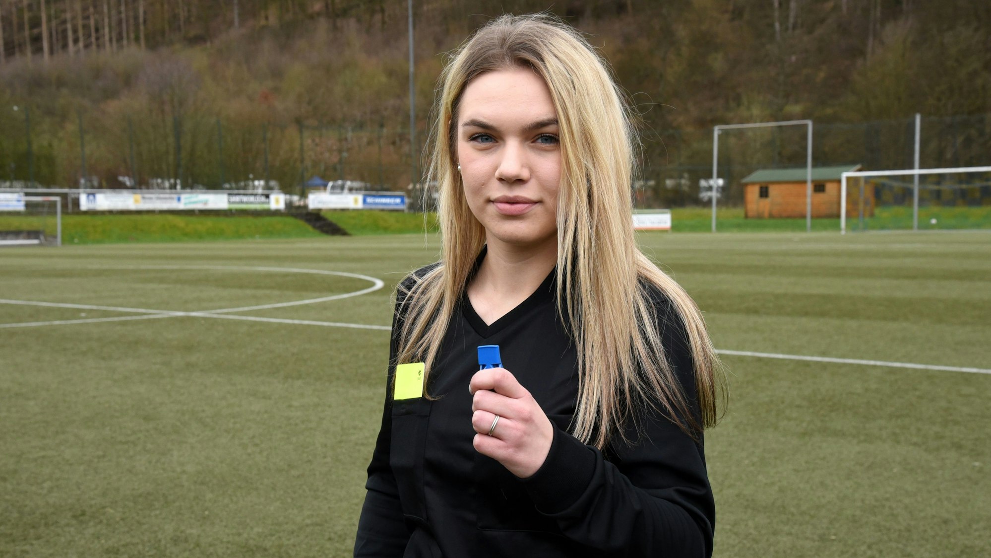 Eine Schiedsrichterin steht allein auf einem Fußballplatz.