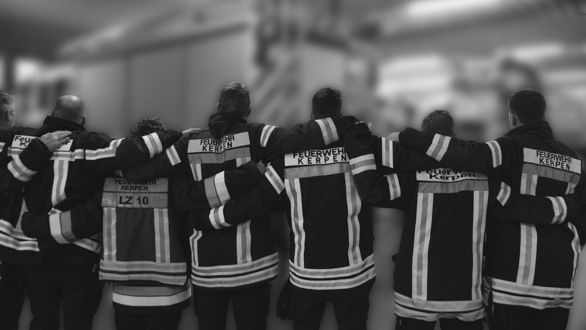 Das Foto zeigt Mitglieder der Kerpener Feuerwehr. Sie bilden eine Kette und legen die Arme auf die Schultern ihres Nebenmannes.