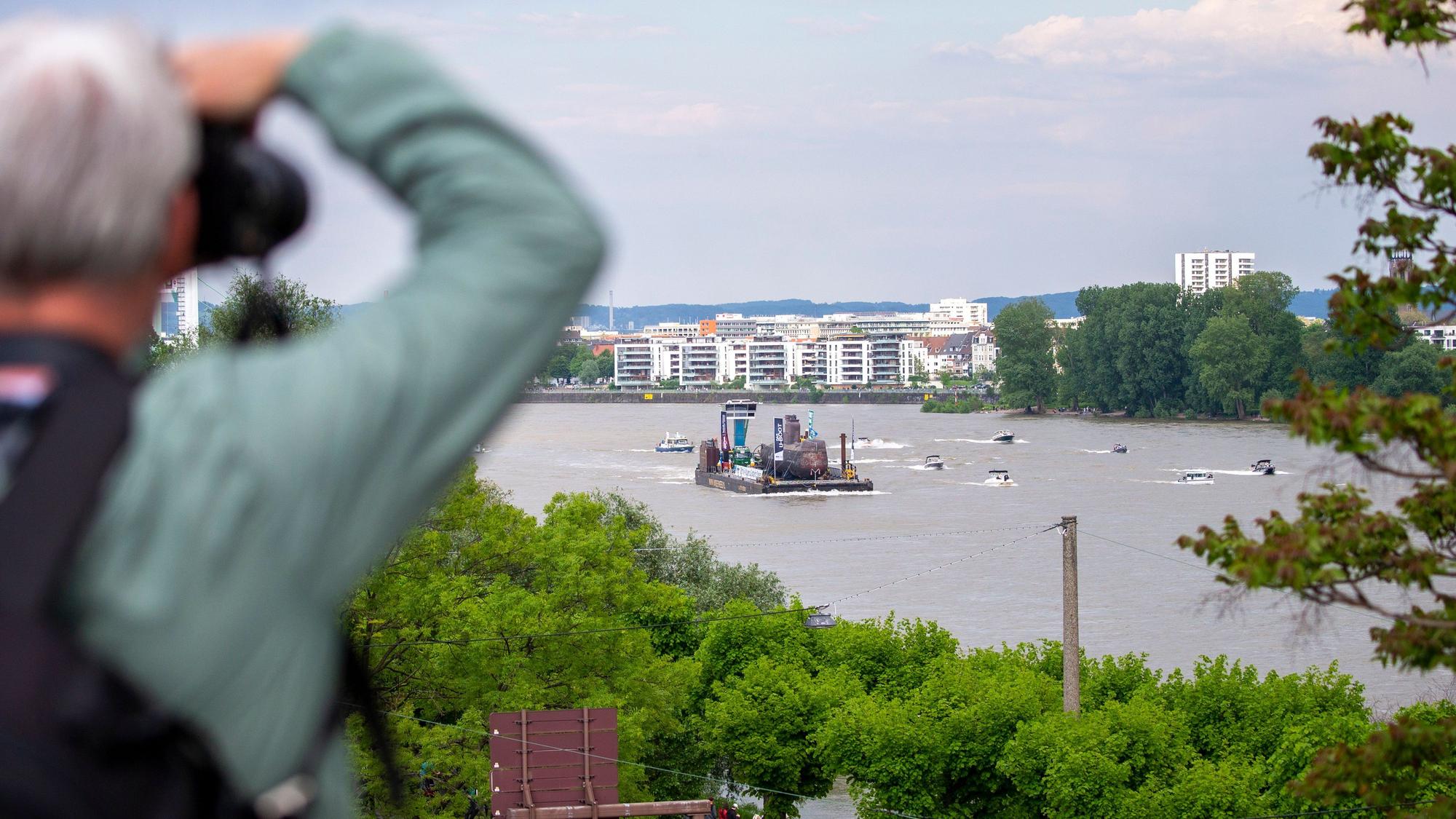 Viele kleine Boote fahren neben dem Lastenträger mit dem U-Boot auf dem Rhein in Köln.