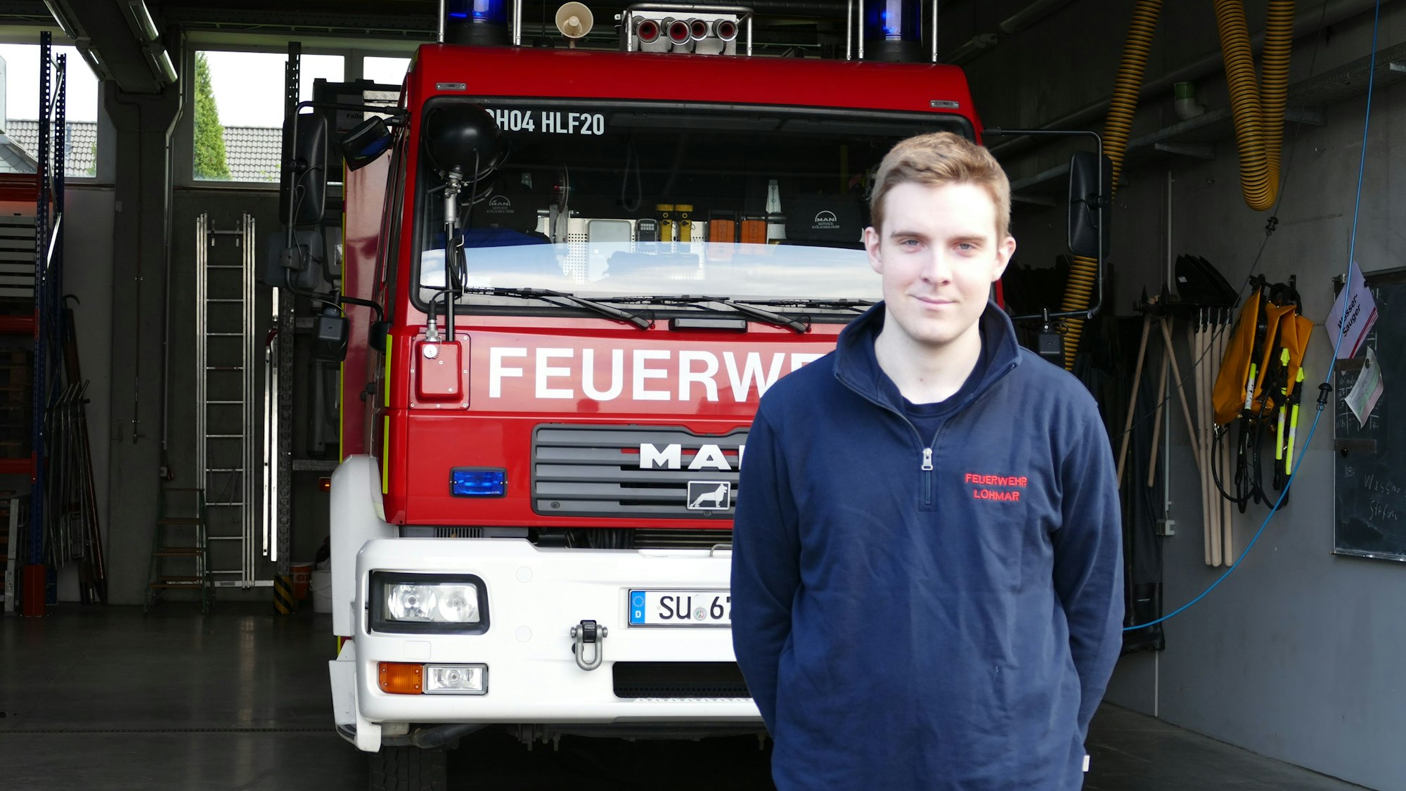 Ein junger Mann steht vor einem Löschfahrzeug der Feuerwehr Lohmar.