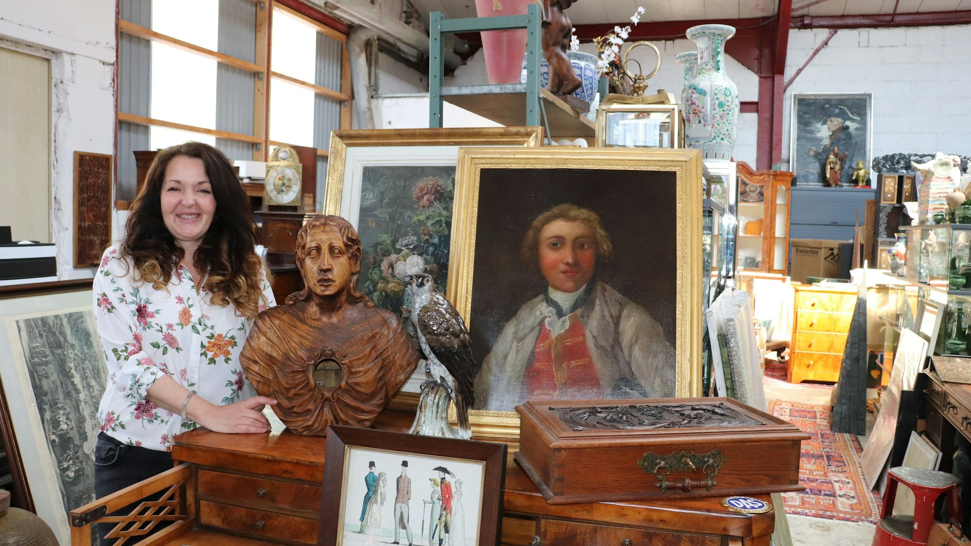 Linda Brovot steht in ihrer neuen Antiquitätenhalle in Köln-Rodenkirchen inmitten alter Möbel und Kunstwerke.