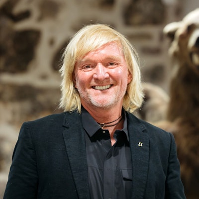 Andreas Kieling, Naturfotograf und Tierfilmer, steht neben einem Präparat eines Grizzlybären.