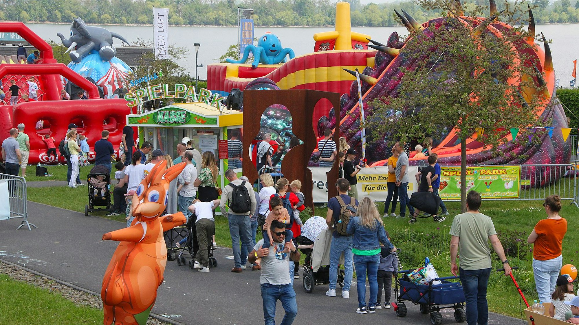 „Jump im Park“ in Zülpich ist ein Hüpfburgenfestival. Vor einer Vielzahl an verschiedenen Hüpfburgen sind junge wie erwachsene Besucher und Besucherinnen zu sehen.