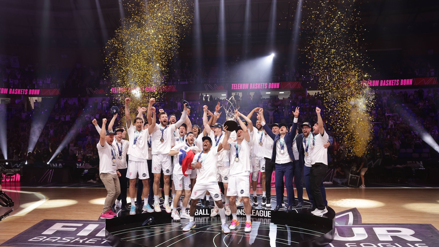 Die Spieler der Telekom Baskets Bonn stehen auf einem Podest und feiern ihren Sieg.