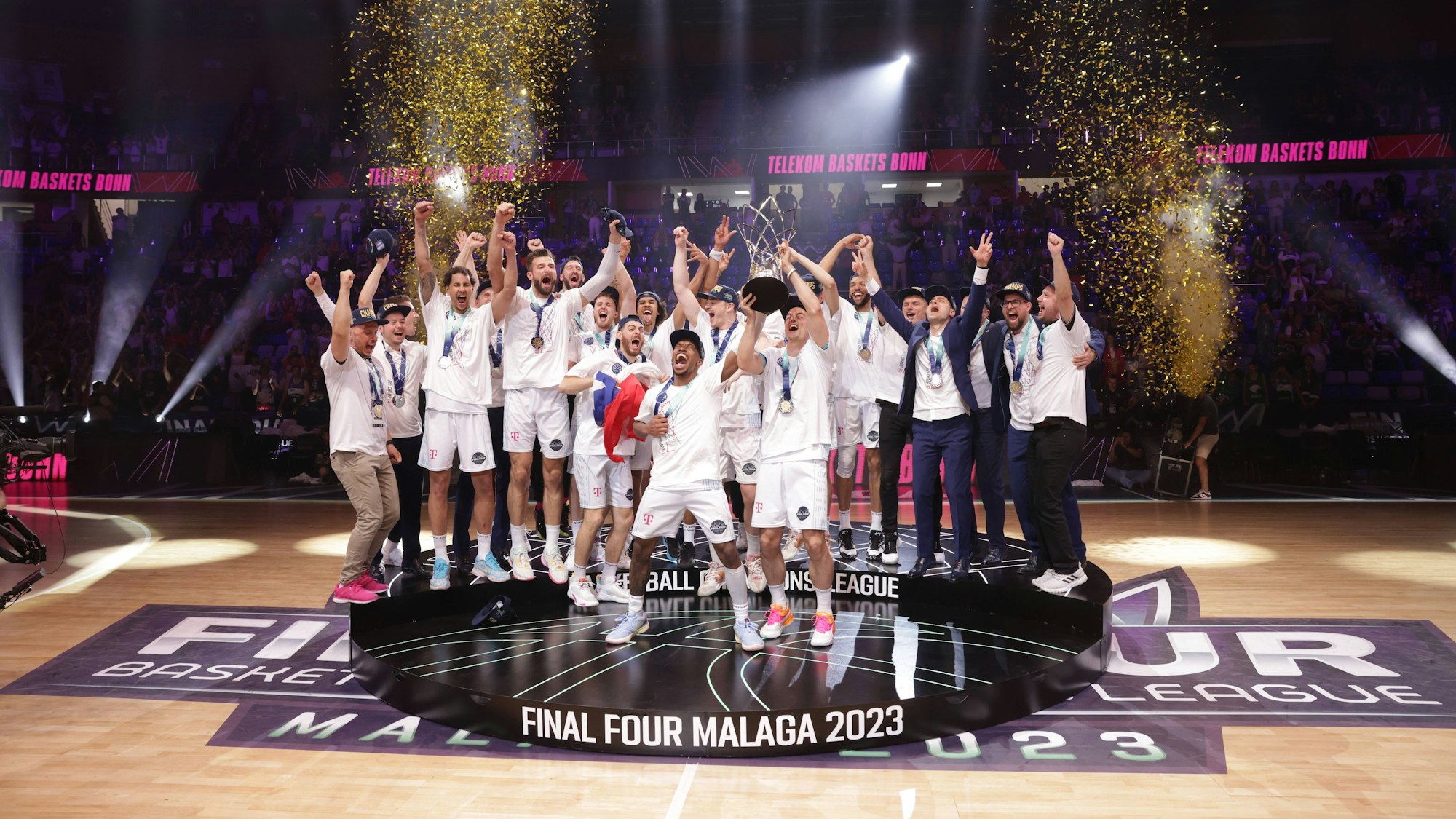 Die Spieler der Telekom Baskets Bonn stehen auf einem Podest und feiern ihren Sieg.