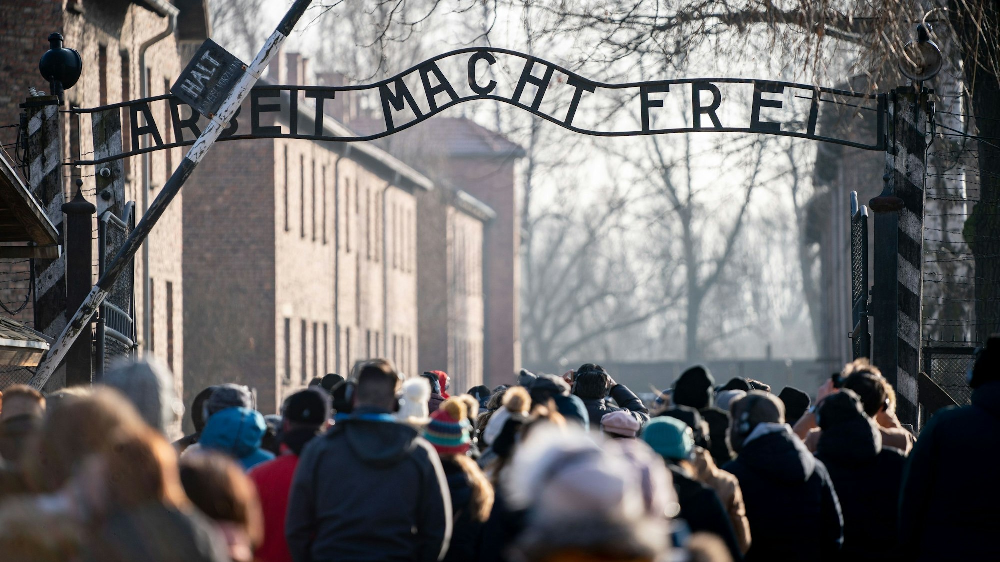 Besucher gehen durch den Eingang des früheren Konzentrationslagers Auschwitz. Zwei Schüler aus Sachsen sollen den sogenannten Hitler-Gruß in Auschwitz gezeigt haben. (Symbolbild)