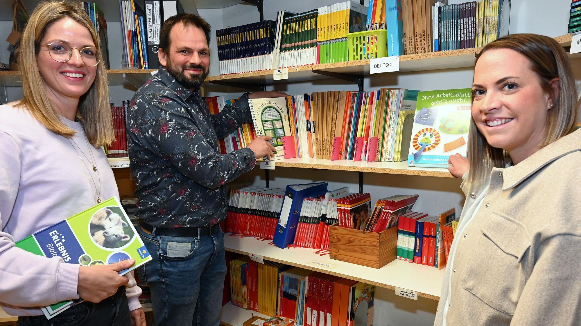 Lisa Dross, Johannes Dörfel und Michèle Kogelheide vor einem prall gefüllten Bücherregal.