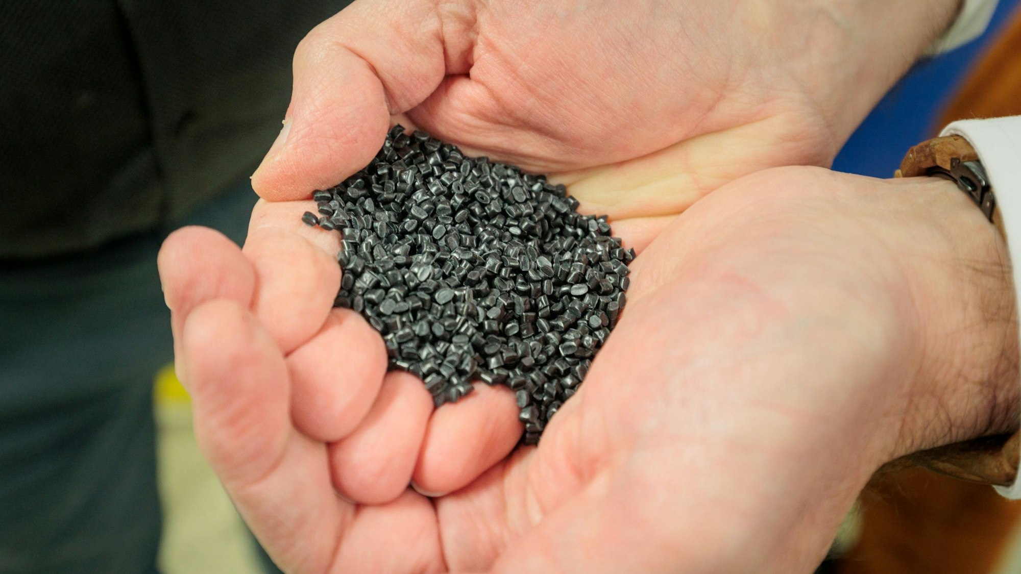 Zwei Hände halten das kleinteilige Granulat.