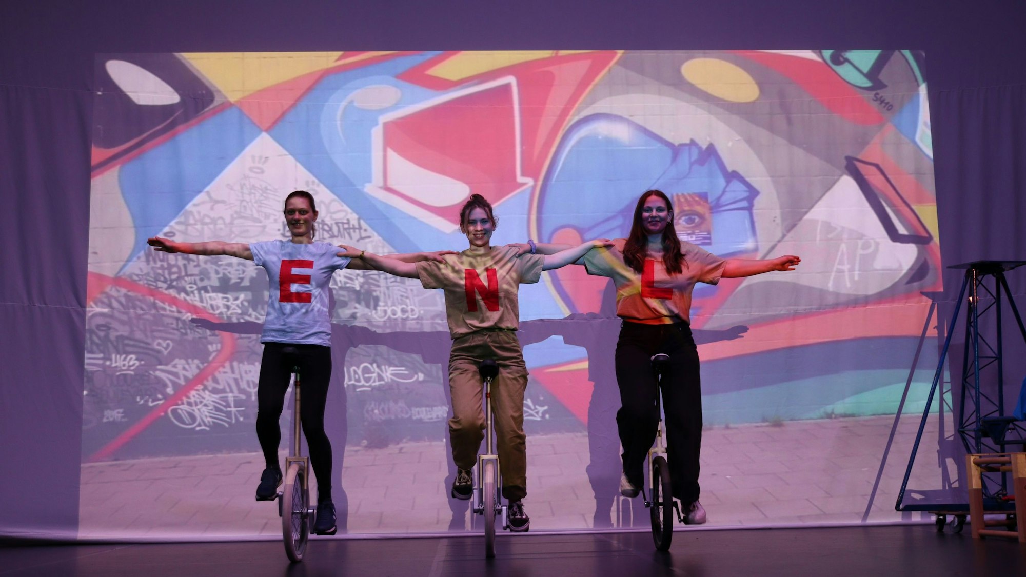 Drei Mitglieder des Circus Radelito auf Einrädern auf der Bühne.