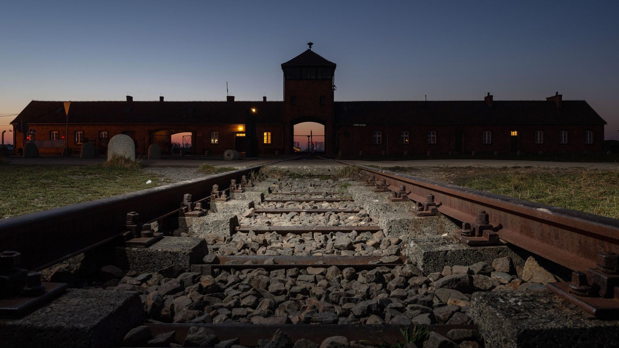 Blick von Eisenbahnschienen auf das Eingangsportal des ehemaligen Konzentrationslagers Auschwitz-Birkenau.