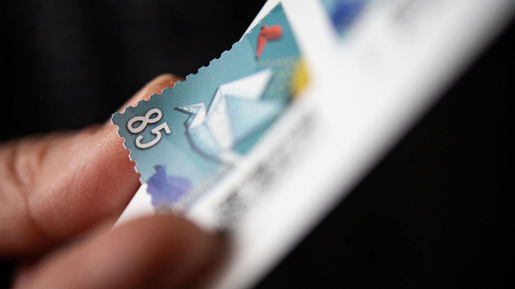 Eine Frau löst eine 85 Cent Briefmarke von einem Bogen. Das jetzige Porto gilt seit Anfang 2022, als sich der Inlandsstandardbrief von 80 auf 85 Cent verteuerte. Das jetzige Porto läuft planmäßig Ende 2024 aus.