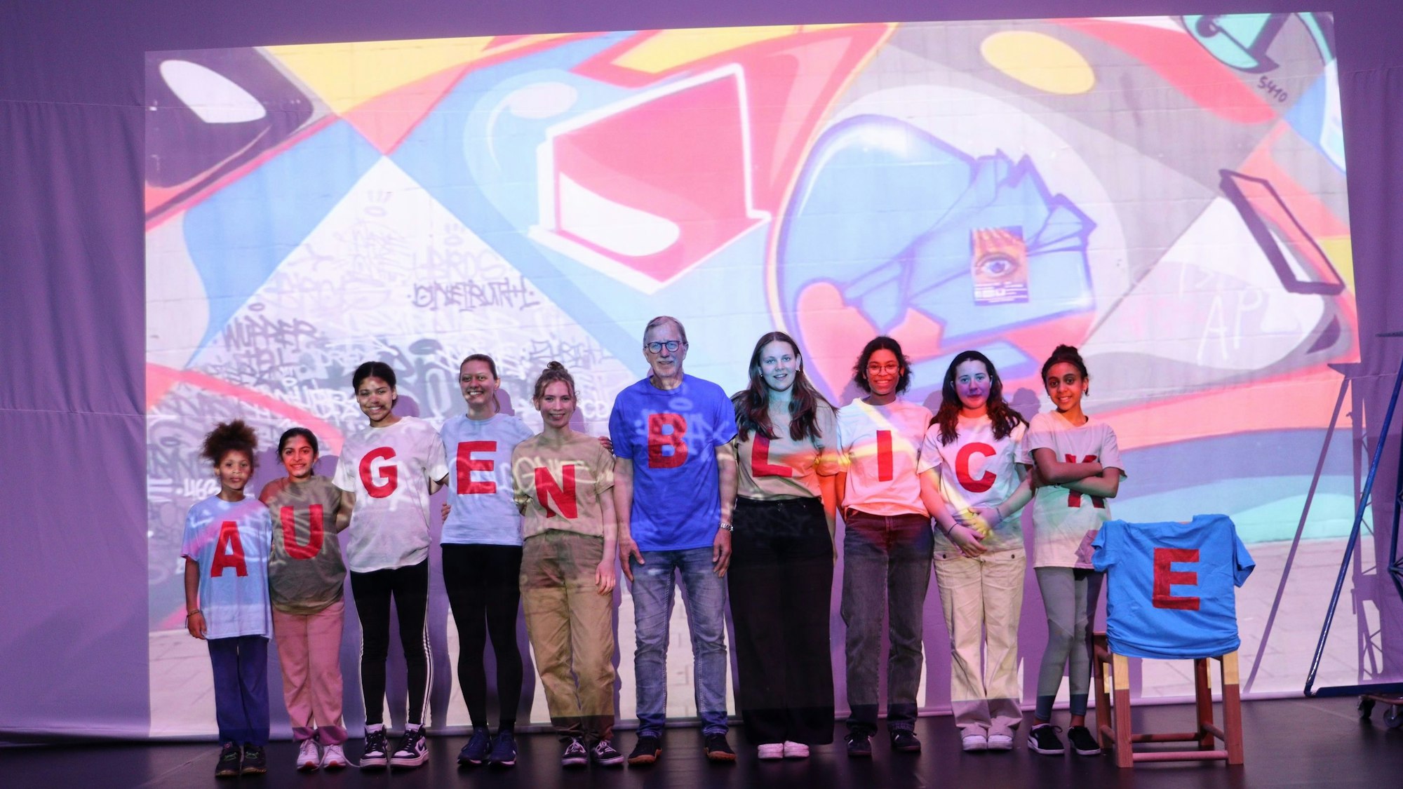 Die Mitglieder des Circus Radelito stehen auf einer Bühne vor einer Leinwand.