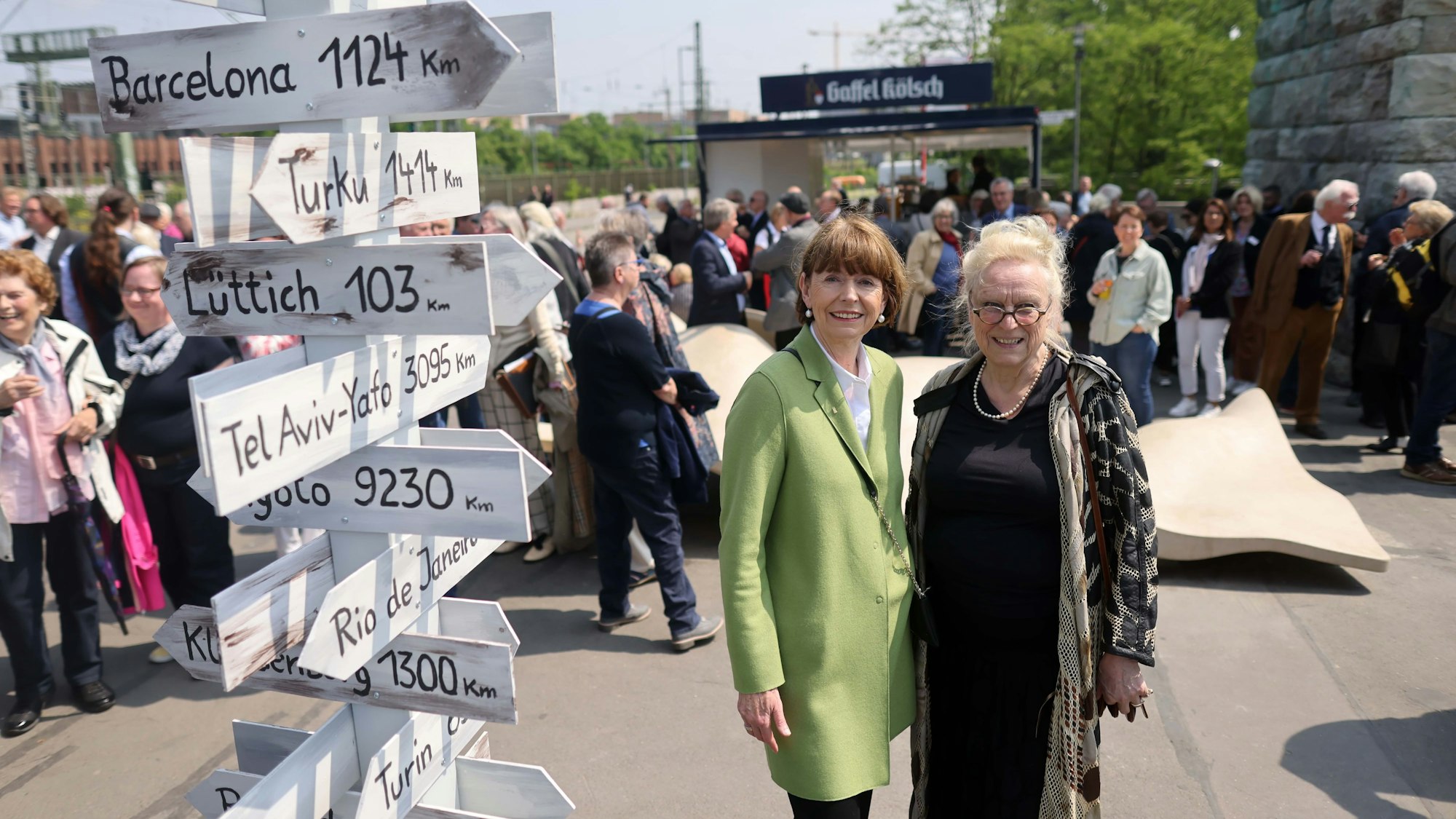 Henriette Reker und Claudia Burger an einem provisorischen Städtepartner-Wegweiser.