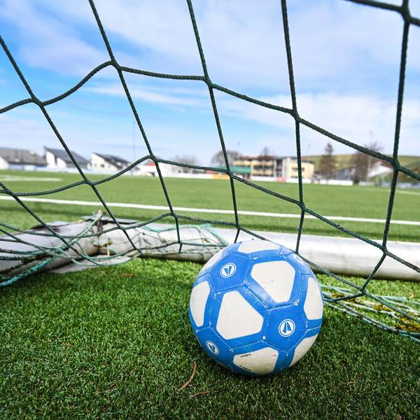 Ein Fußball liegt in einem Tor, das auf einem leeren Fußballplatz steht.