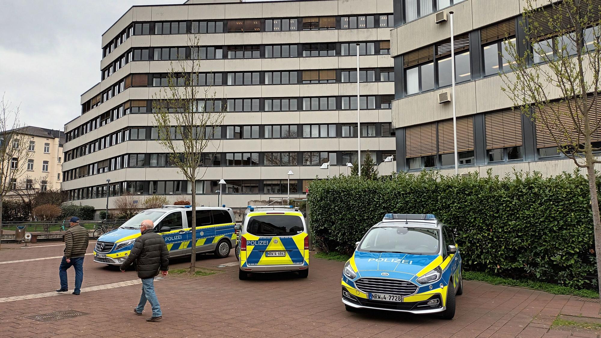 Vor dem Amtsgericht Siegburg stehen drei Poilizeiwagen. Zwei Personen laufen daran vorbei.