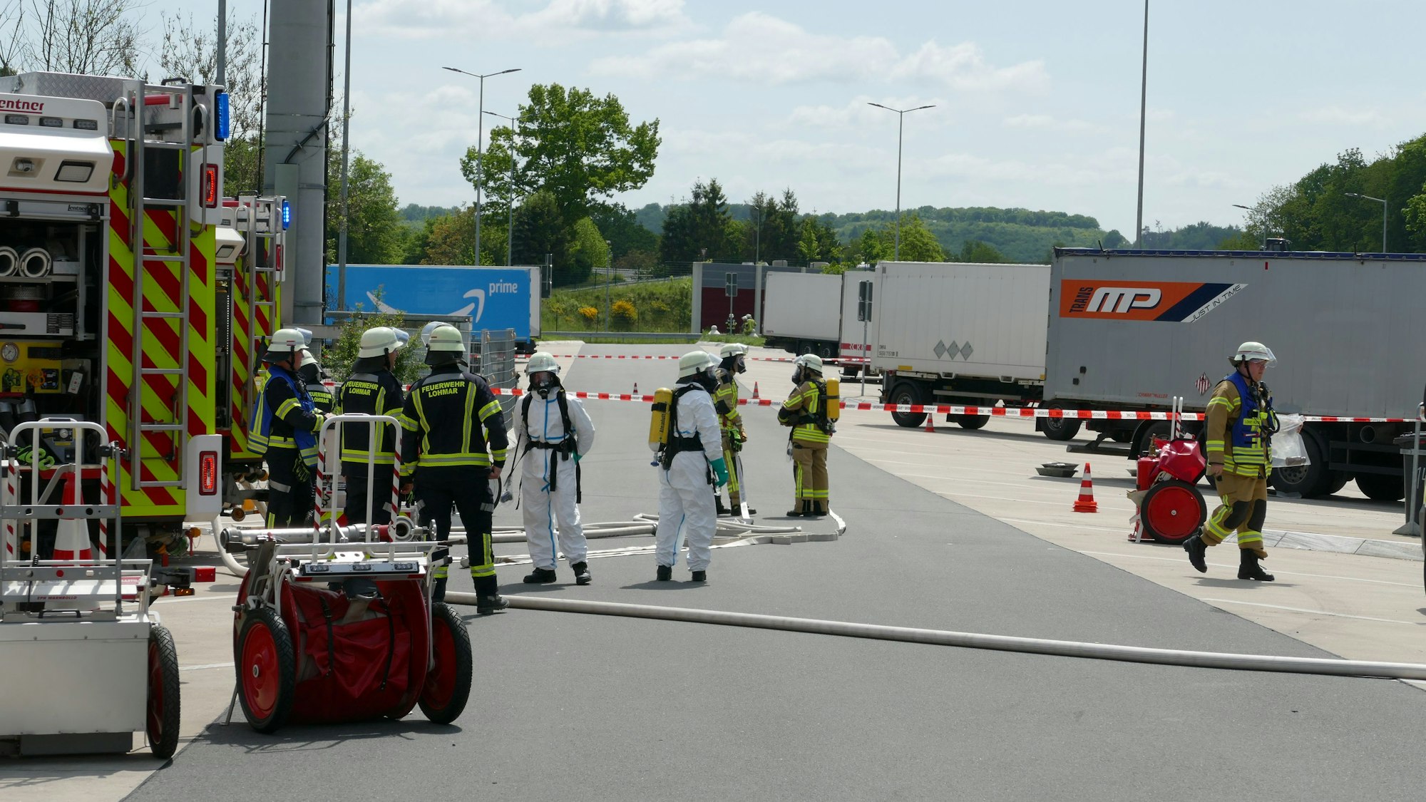 Feuerwehrleute in Schutzanzügen stellen Auffangbehälter unter den Lkw.