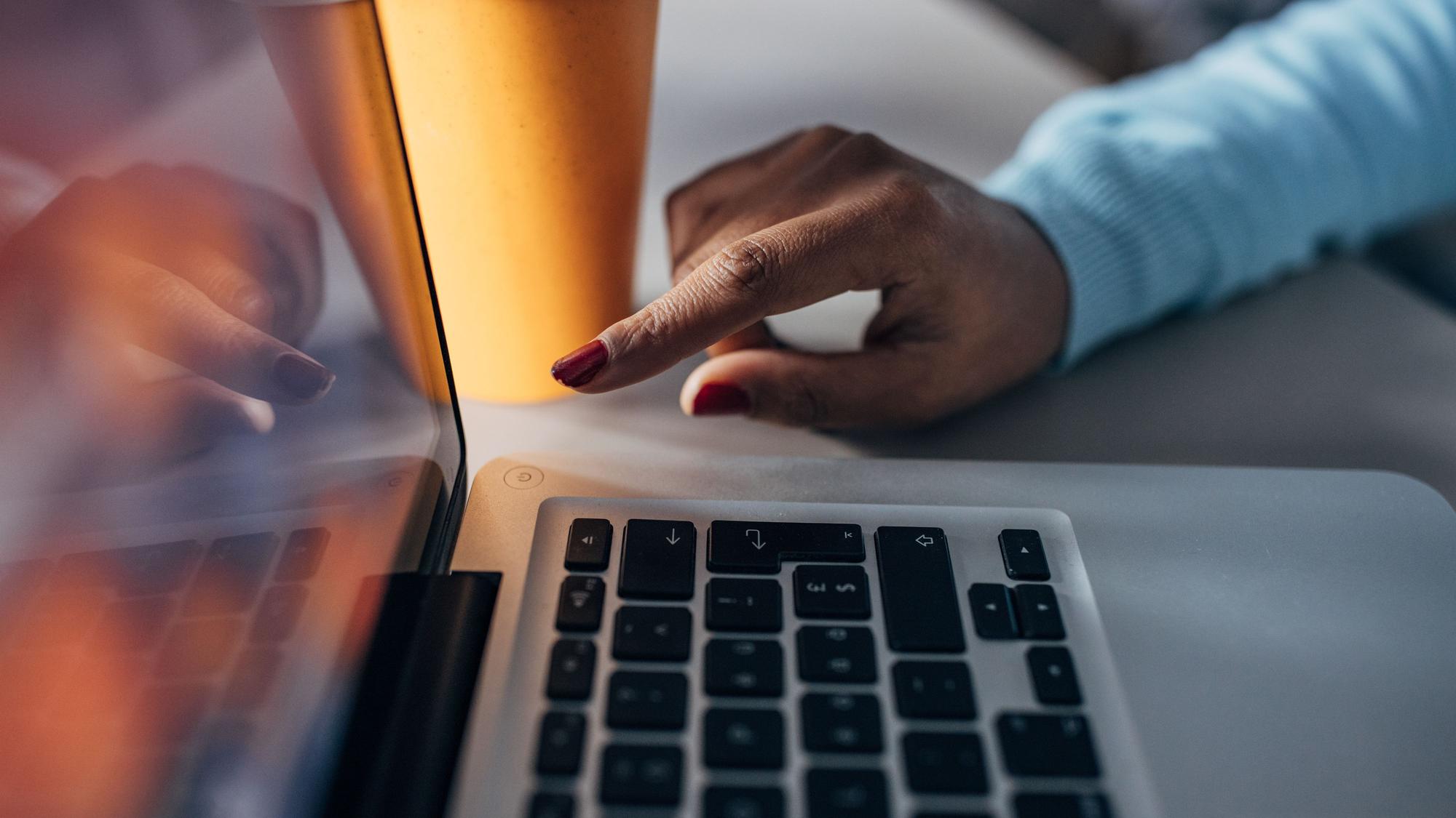 Eine Frau drückt auf den Aus-Schalter am Laptop
