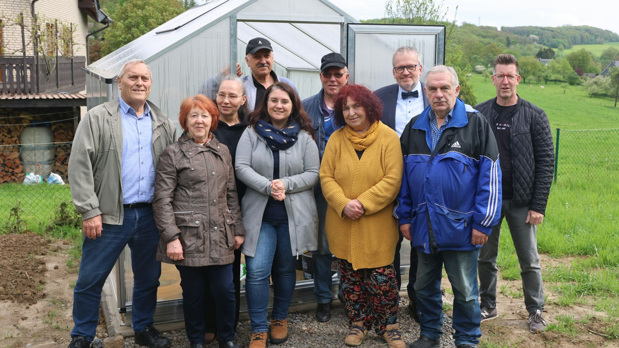 Eine Gruppe steht vor einem neuen Gewächshaus.