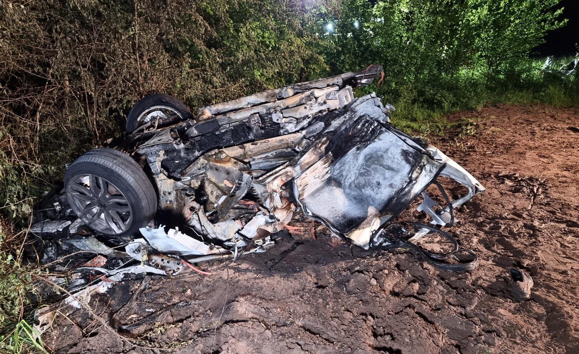 18.05.2023, Niedersachsen, Lengerich: Der hintere, abgerissene und ausgebrannte Teil des Unfallautos. Bei einem schweren Unfall sind ein Autofahrer und sein zwölfjähriger Sohn ums Leben gekommen. Ihr Wagen war mit hoher Geschwindigkeit unterwegs gewesen. In einer Rechtskurve kam das Auto von der Straße ab und krachte mit solcher Wucht gegen einen Baum, dass es in zwei Stücke gerissen wurde und in Flammen aufging. Foto: Ulf Zurlutter/Nord-West-Media/dpa +++ dpa-Bildfunk +++