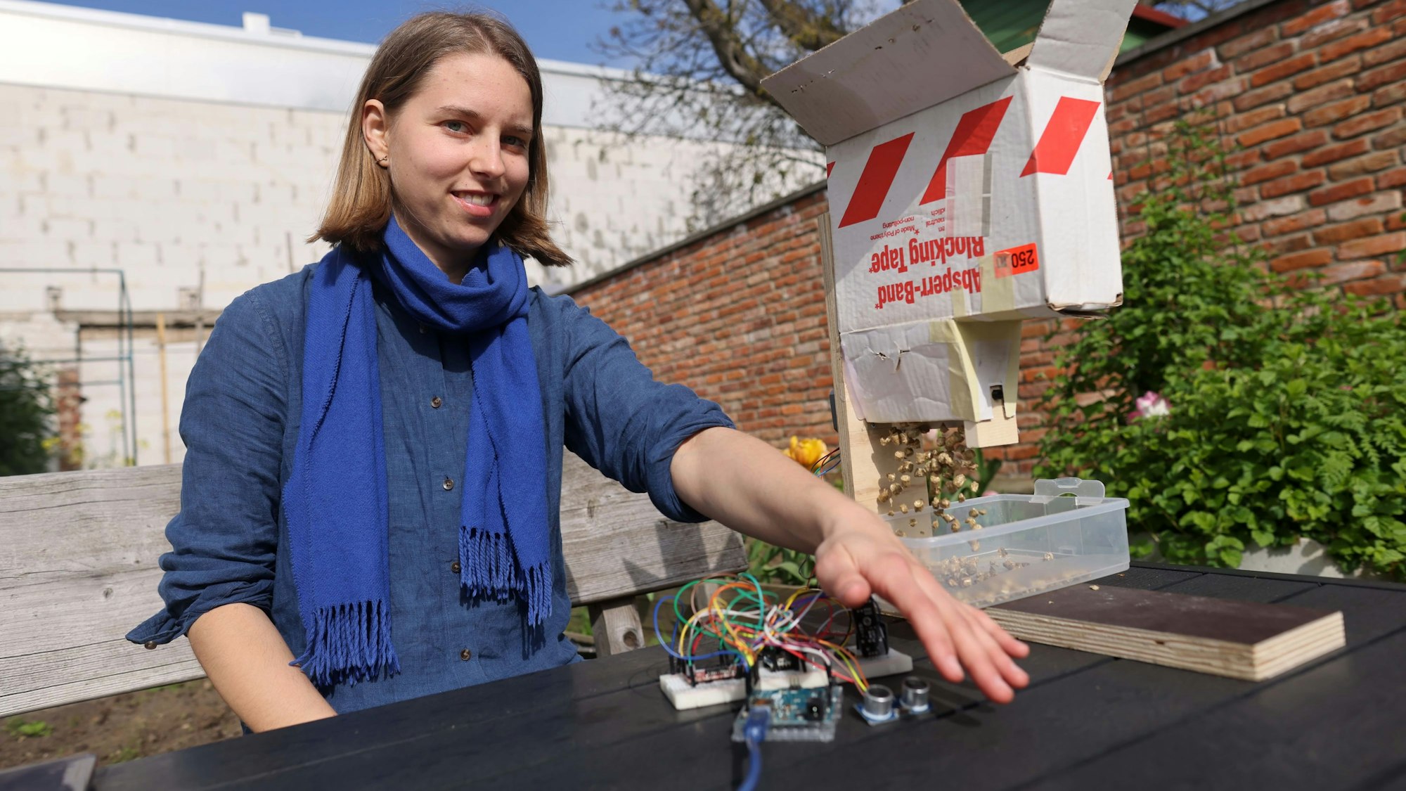 Anastasia Bondar sitzt an einem Tisch und zeigt ihre Erfindung.