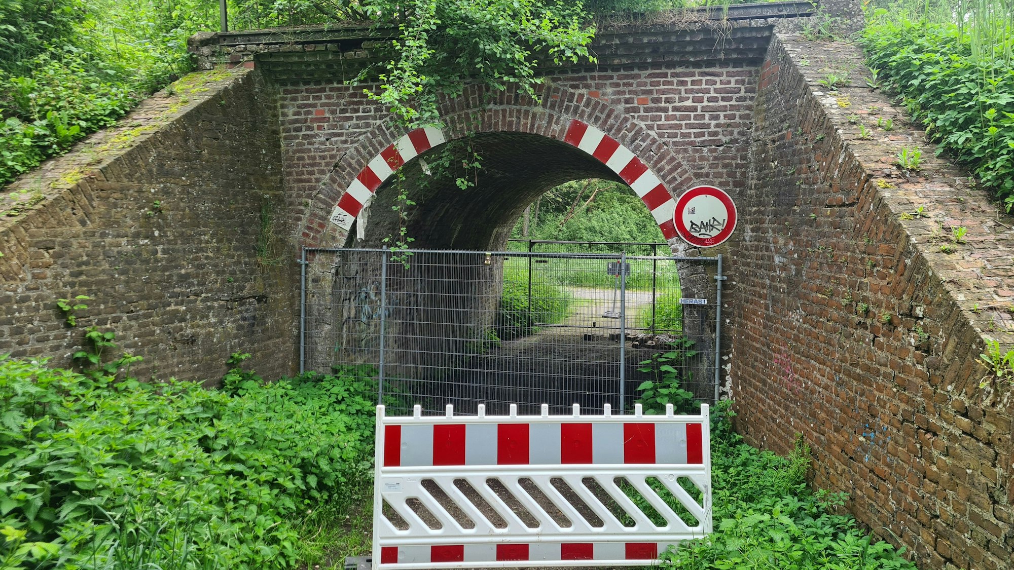 Bauzäune und Baken versperren den Weg unter eine Brücke.