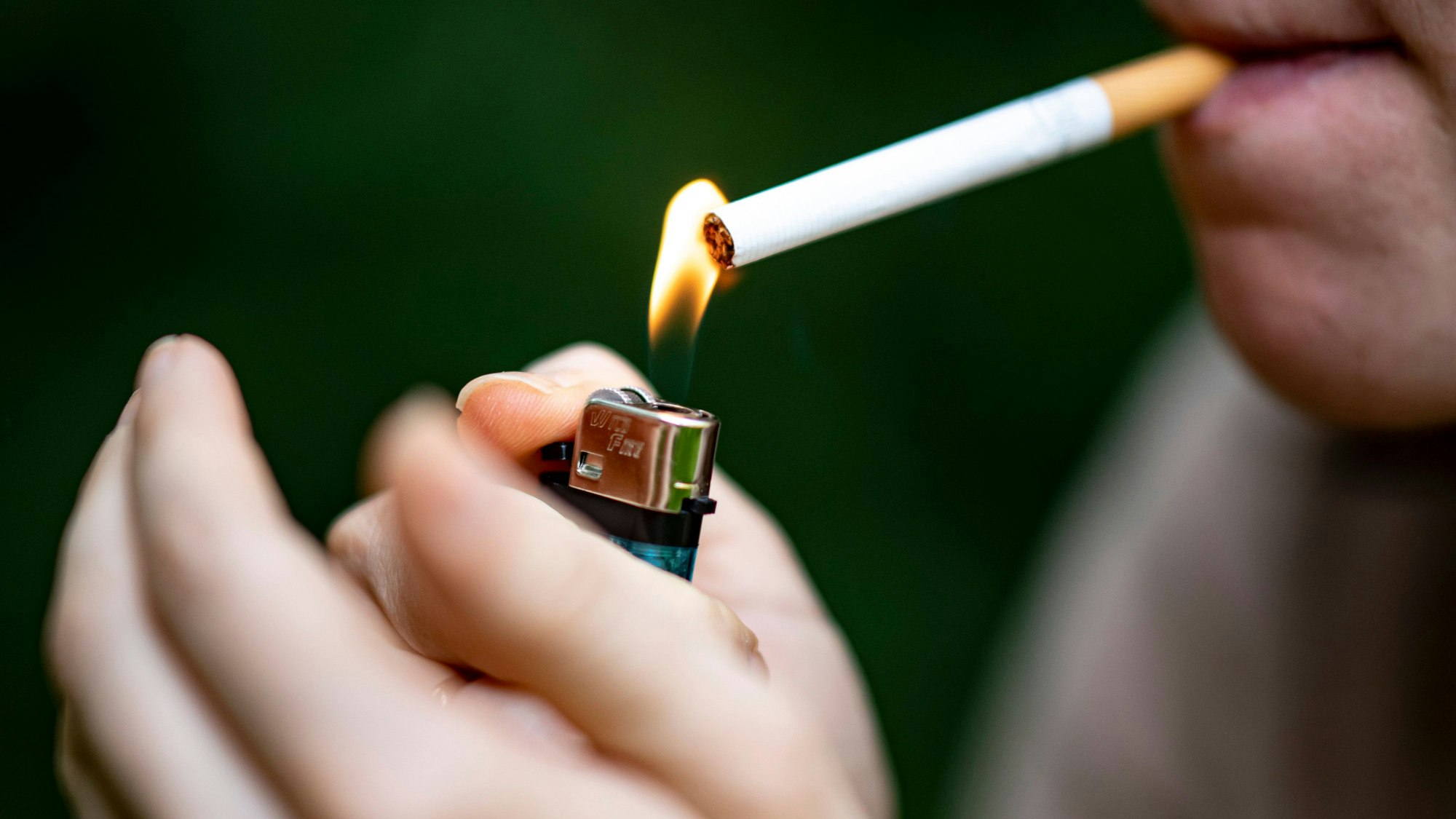 Eine Frau zündet sich mit einem Feuerzeug eine Zigarette an.