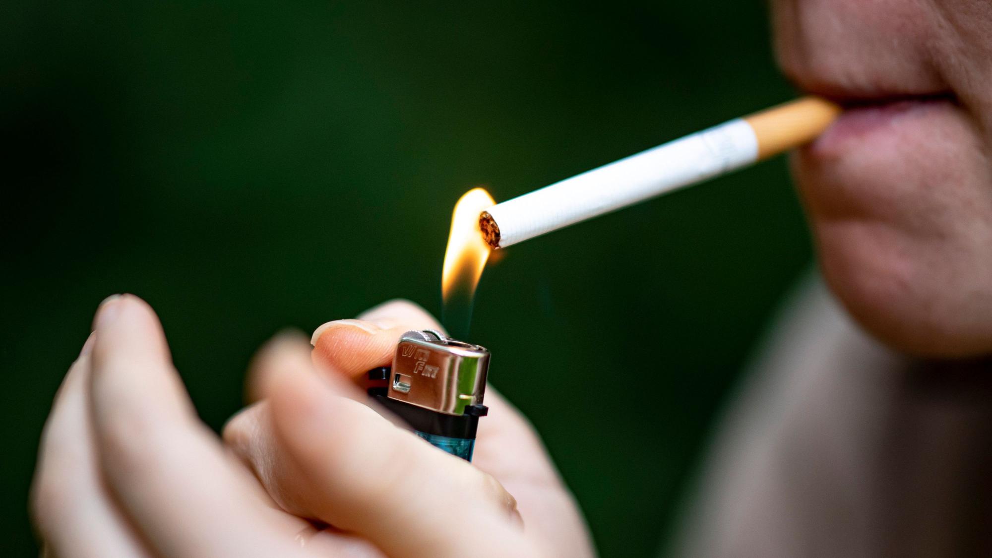 Eine Frau zündet sich mit einem Feuerzeug eine Zigarette an.
