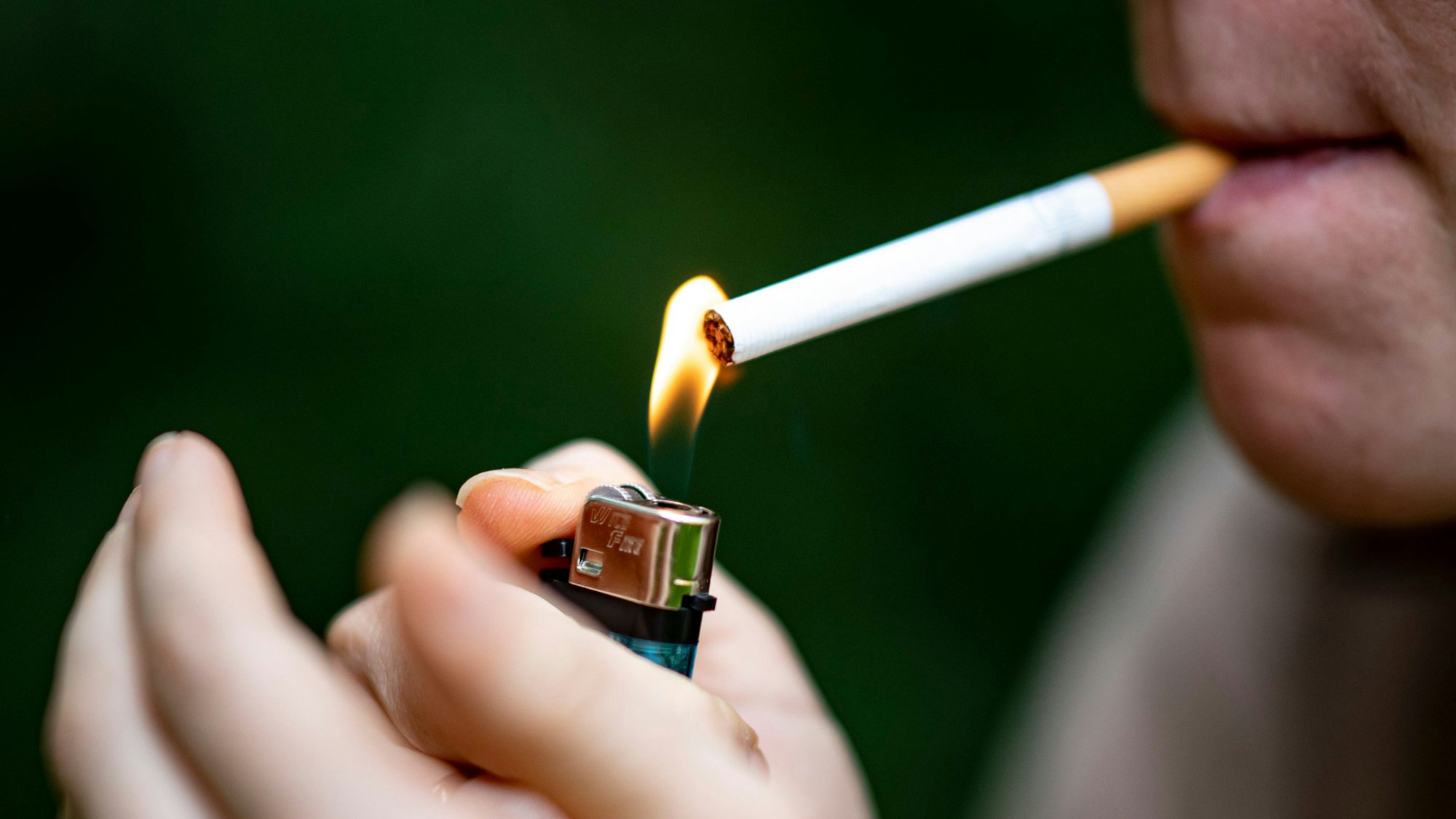 Eine Frau zündet sich mit einem Feuerzeug eine Zigarette an.