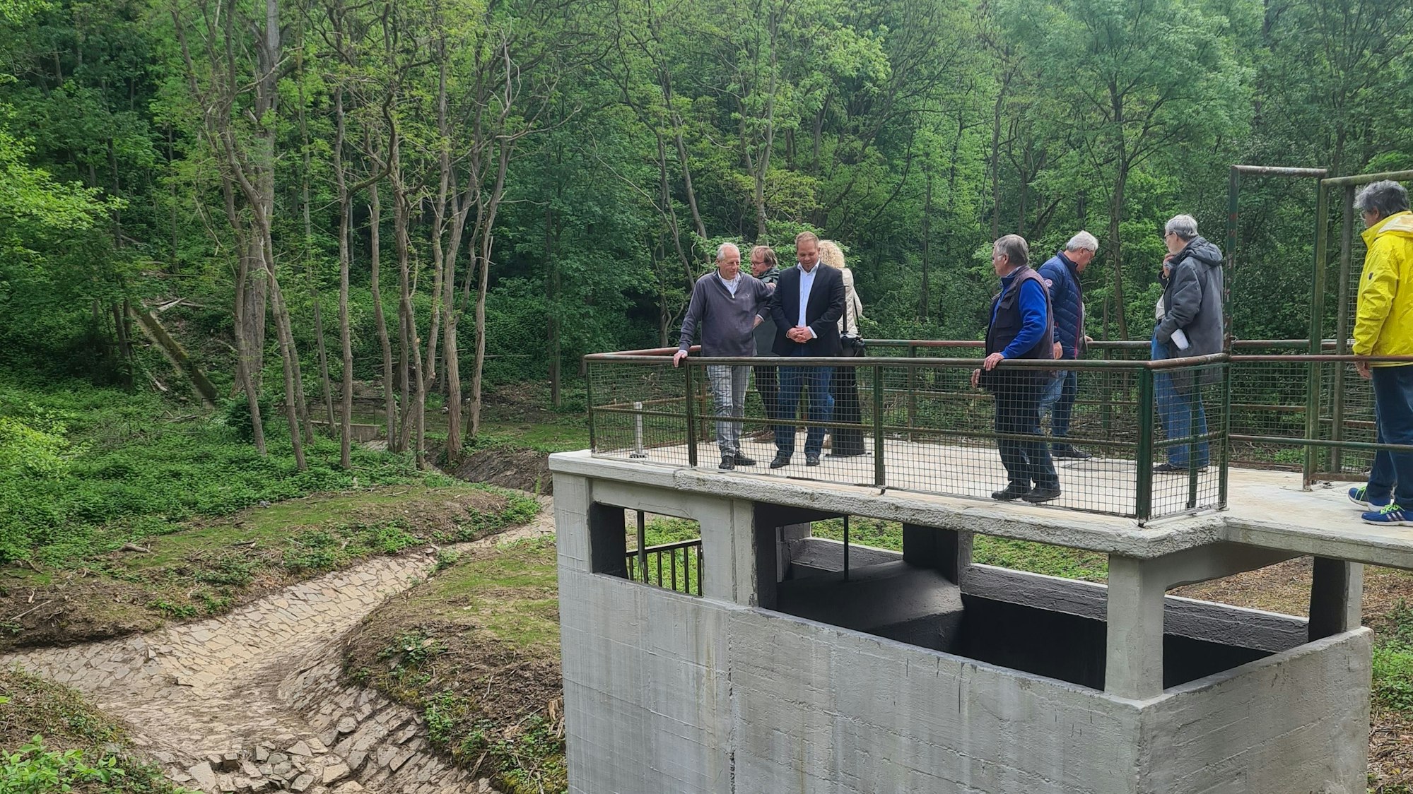 Das Auslaufbauwerk am Hochwasserrückhaltebecken wird von mehreren Menschen inspiziert.