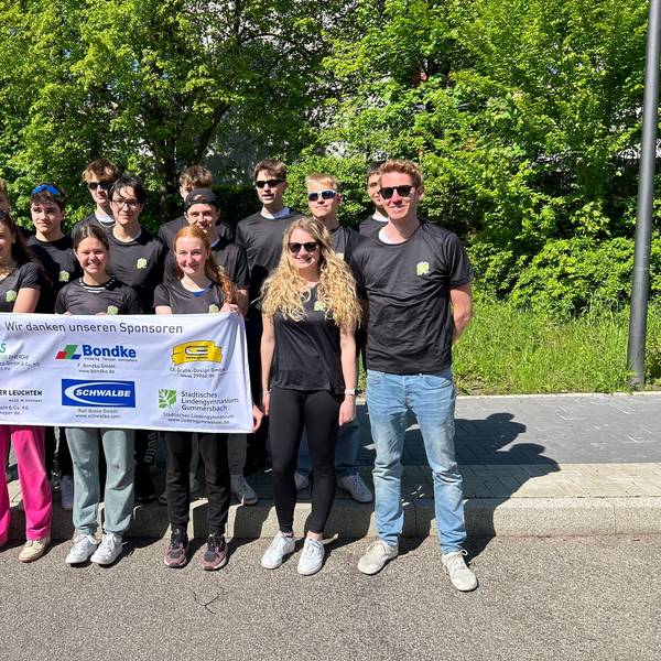 Eine Gruppe Schülerinnen und Schüler steht mit einem Sponsoren-Banner zusammen.