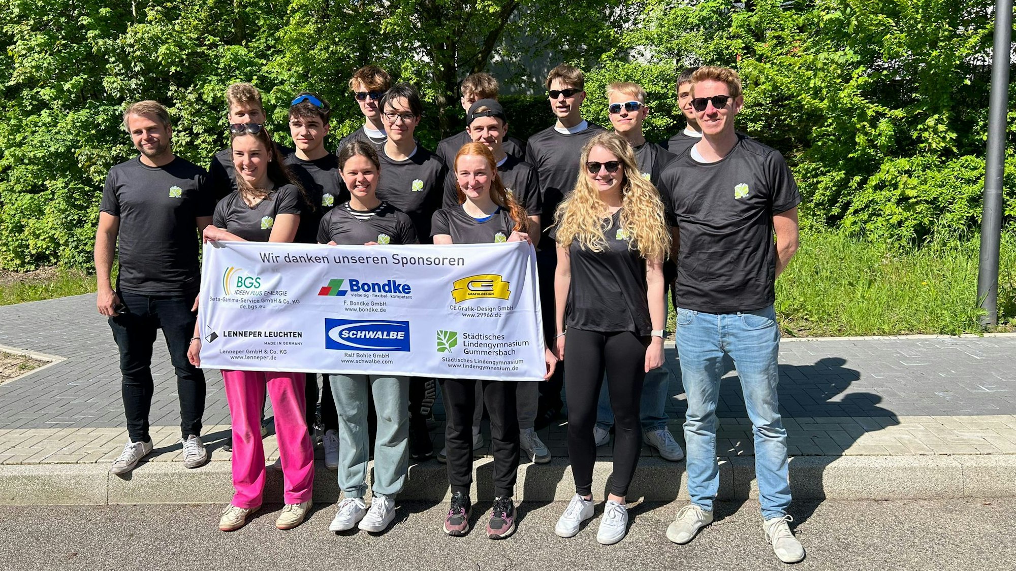 Eine Gruppe Schülerinnen und Schüler steht mit einem Sponsoren-Banner zusammen.